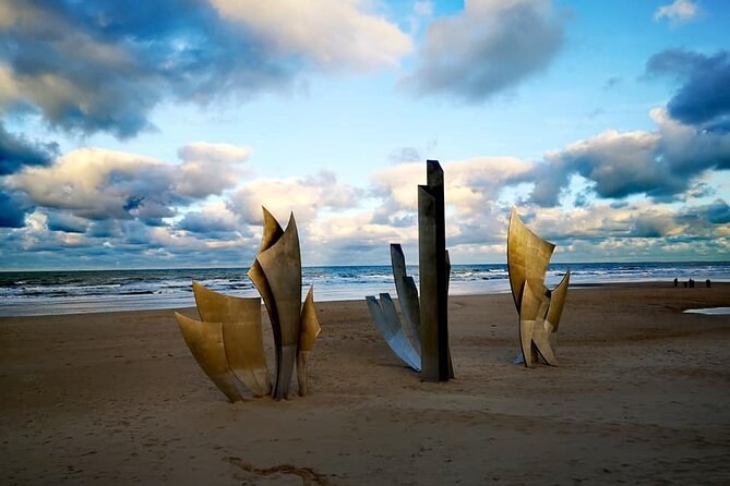 The Les Braves sculpture standing on the sand at Omaha Beach