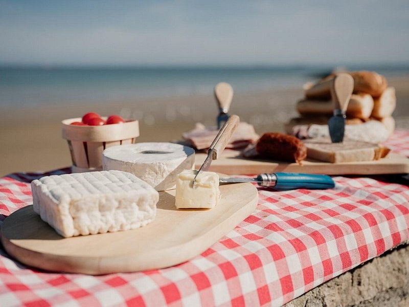 Normandy cheeses and a knife set out on a wooden board
